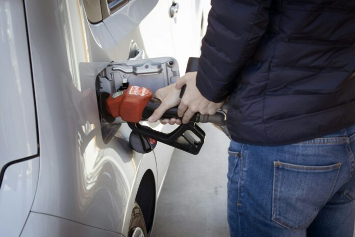 Photo by sippakorn yamkasikorn a man pumping gas into his car at a gas station