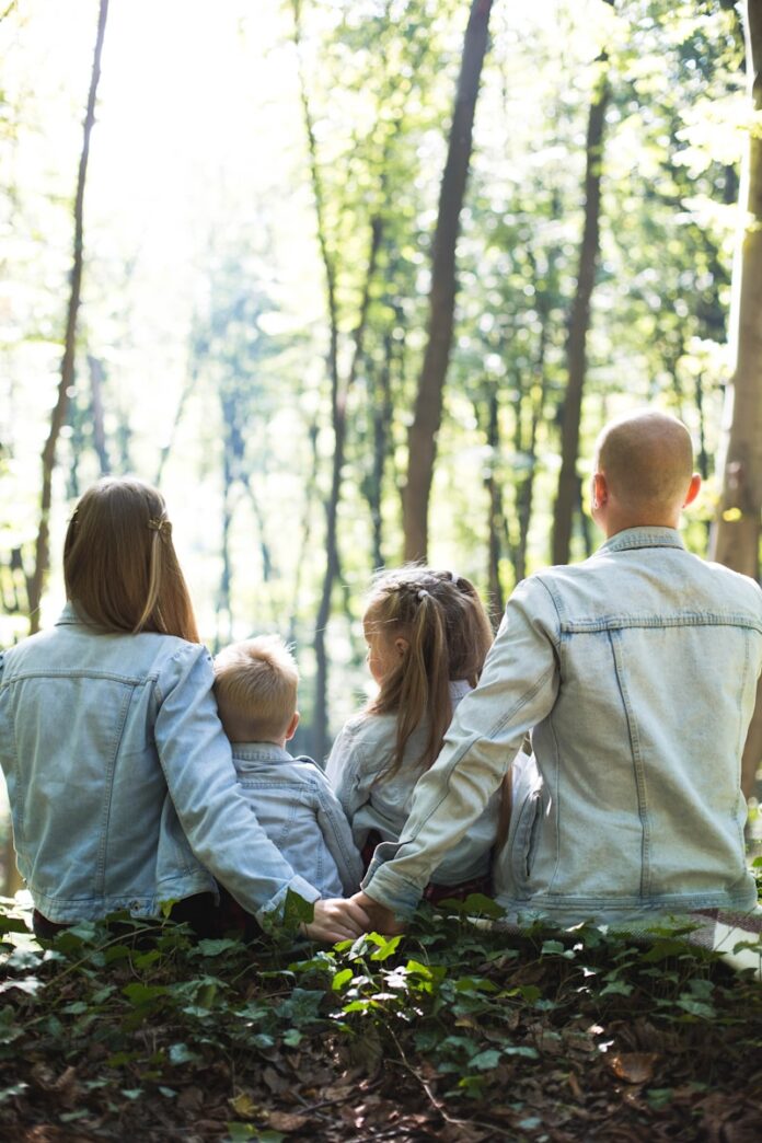 Photo by Ioann-Mark Kuznietsov man and woman holding hands together with boy and girl looking at green trees during day