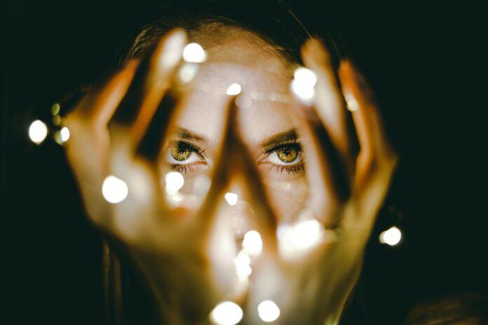 Photo by Lloyd Newman woman holding string lights