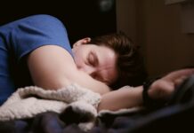 “만성 피로는 단순 피곤이 아닙니다”… 몸이 보내는 위험 신호 5가지 woman in blue shirt lying on bed