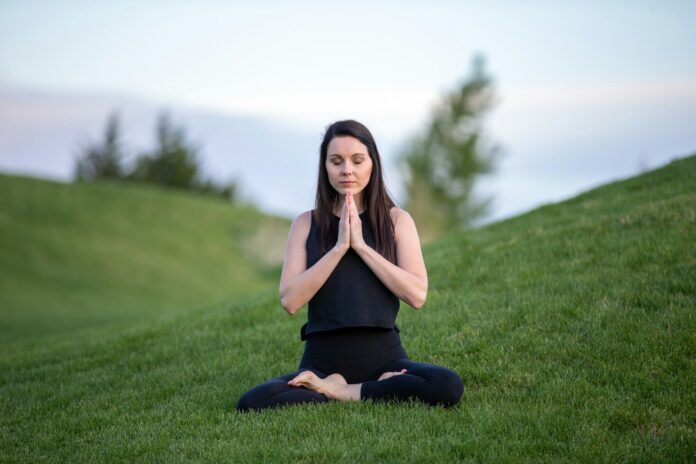 Photo by Benjamin Child woman in black tank top and black pants sitting on green grass field during daytime