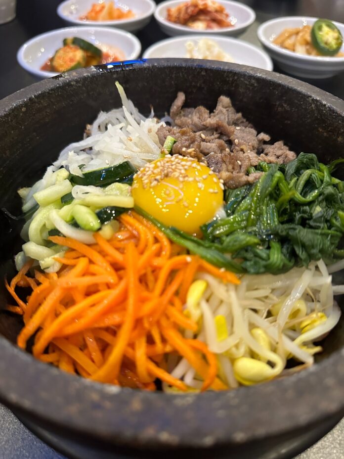 Korean bibimbap with side dishes is served.