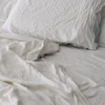 숙면은 습관에서 시작된다…현대인의 건강을 지키는 새로운 수면 루틴 A rumpled white duvet and pillows on a bed.