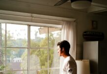 ‘마음 챙김’이 삶을 바꾼다…일상 속 스트레스 줄이는 생활 루틴 man wearing gray and black crew-neck shirt standing and looking out window